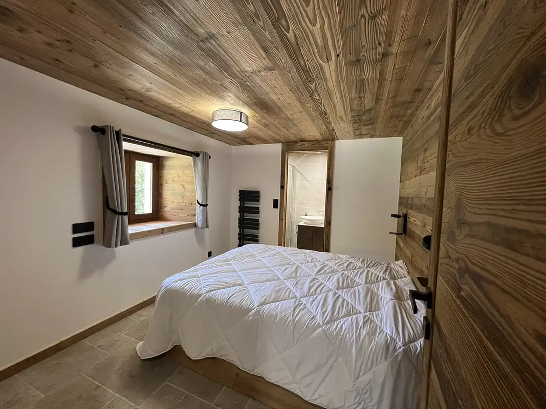  Chambre double spacieuse avec lit king-size, décoration en bois et vue sur la forêt.