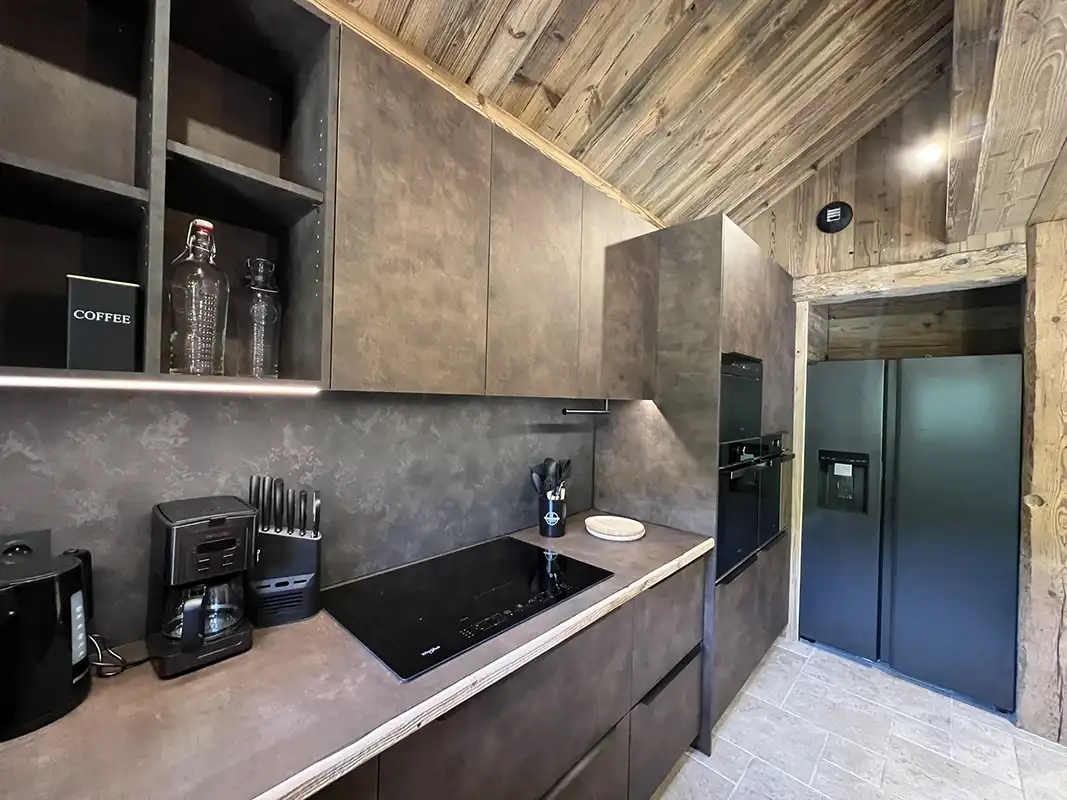 Cuisine moderne équipée avec îlot central, alliant design contemporain et ambiance chalet.