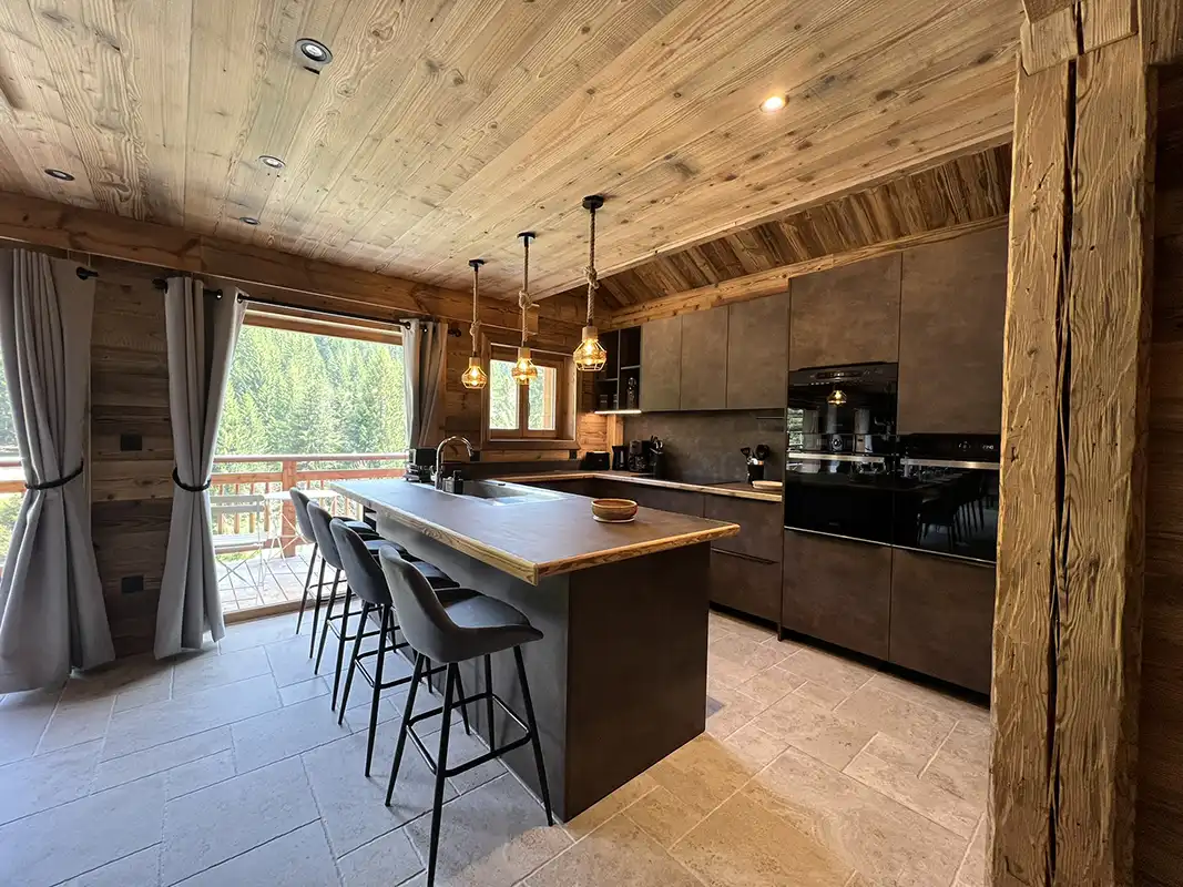 Cuisine moderne équipée avec îlot central, alliant design contemporain et ambiance chalet.