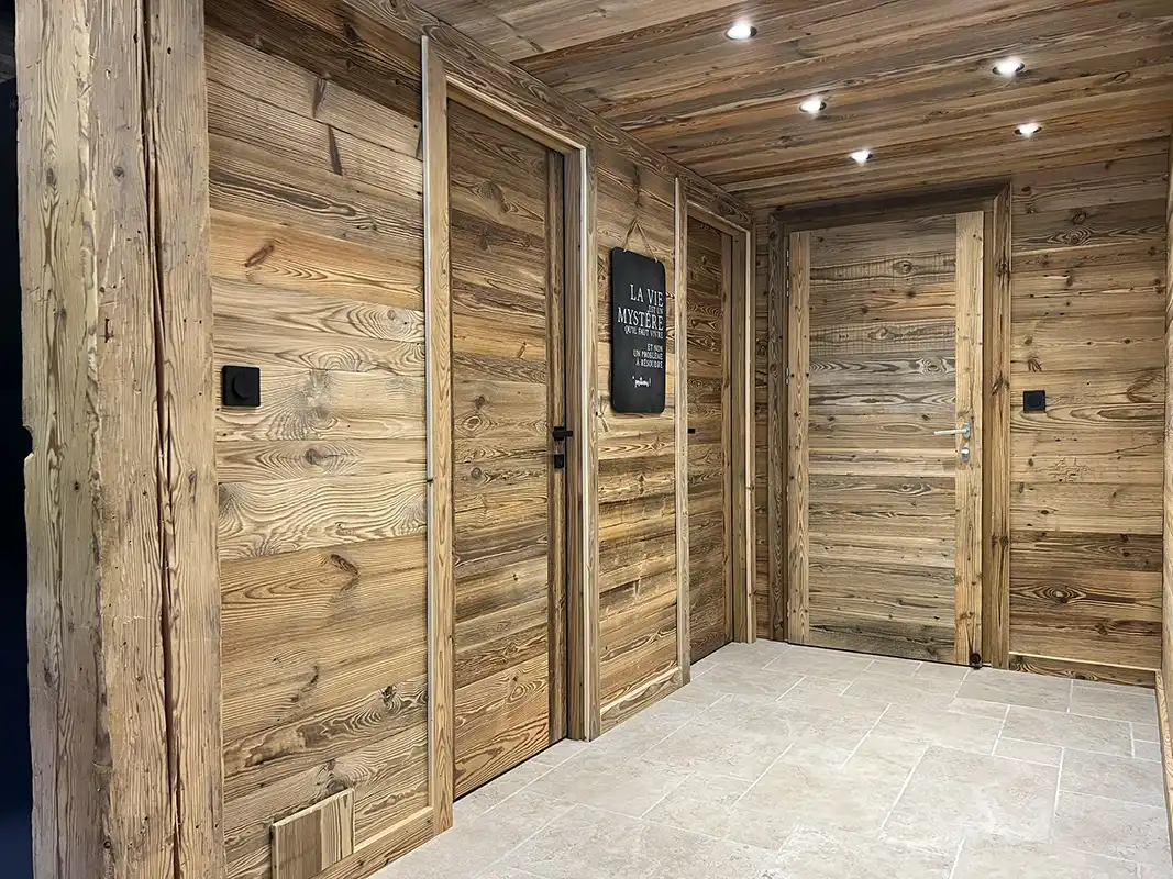 Plafond cathédrale en bois massif avec poutres apparentes dans la pièce principale.