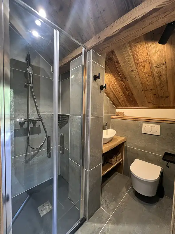 Salle de bains moderne équipée d'une douche à l’italienne et de matériaux naturels.